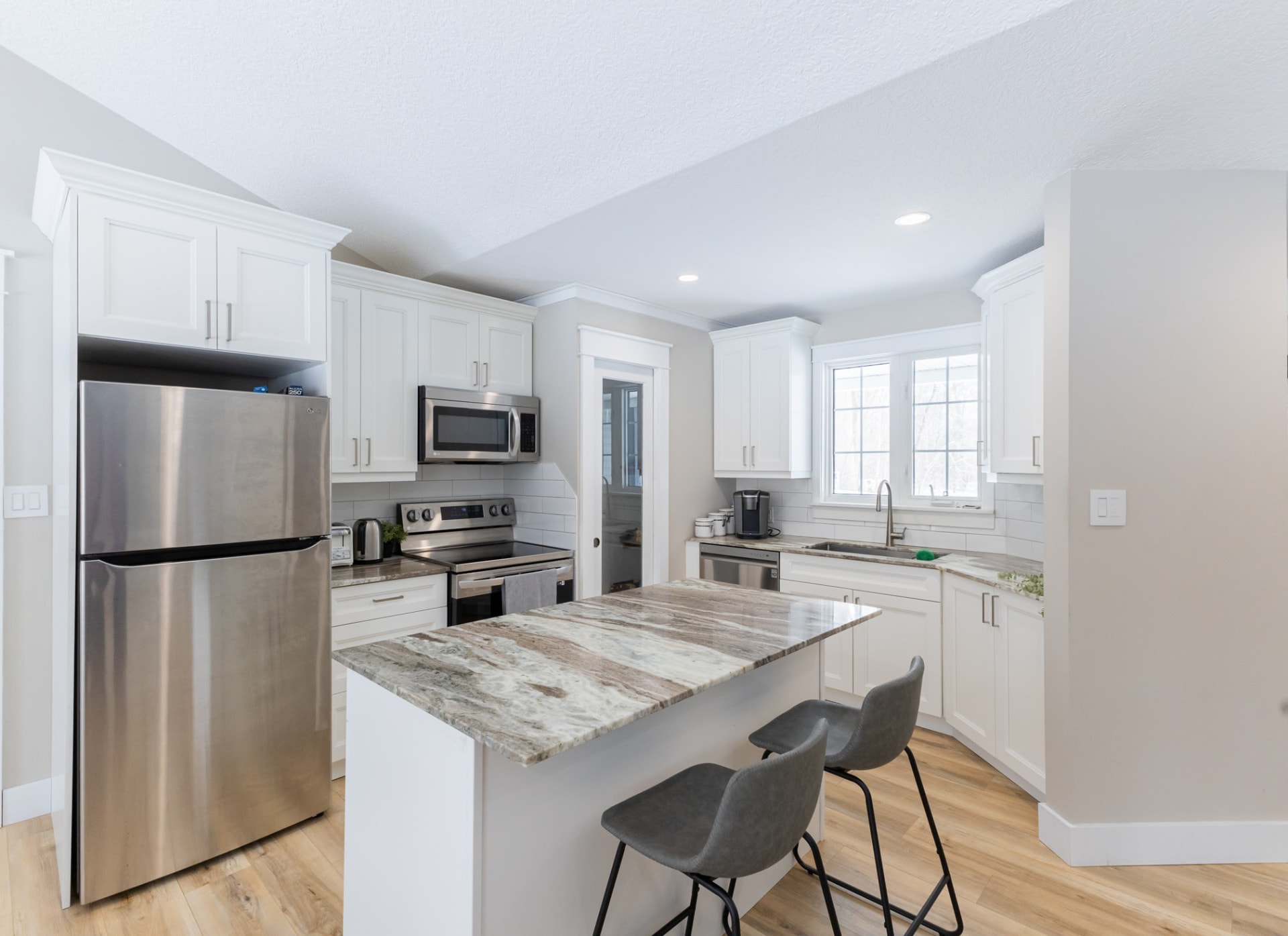 Finished white kitchen with quartzite island, stainless appliances and subway tile backsplash