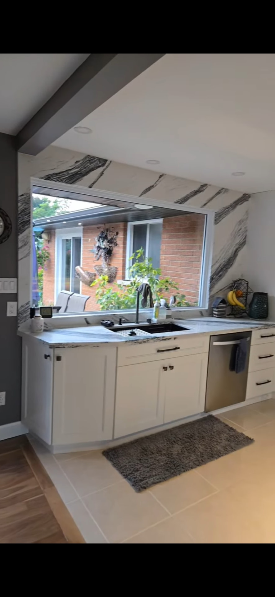 Finished kitchen with white cabinets, marble-veined quartz counters and full-height slab backsplash