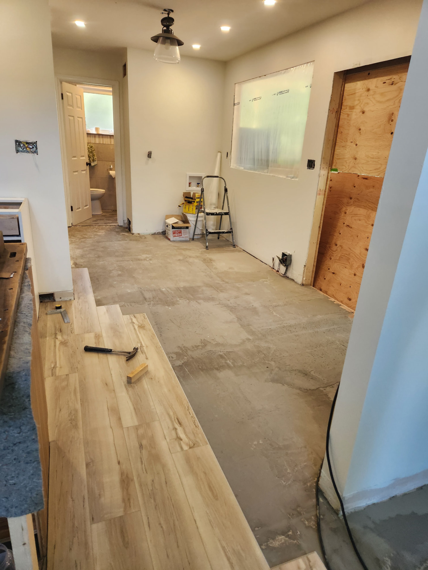Plank flooring going down over the bare subfloor during the kitchen demolition stage