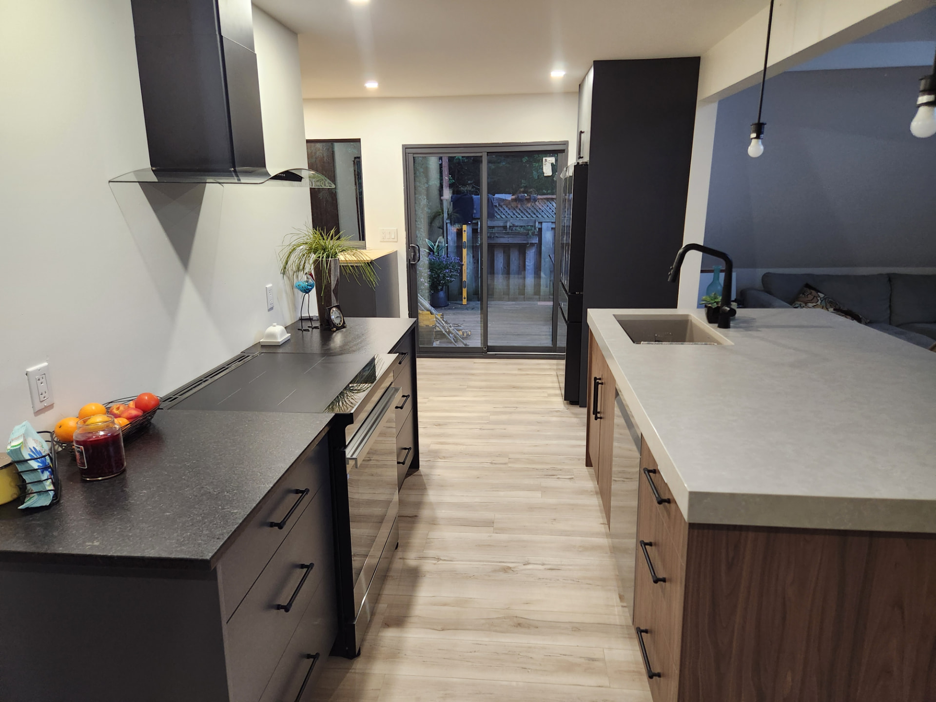 Finished galley view with black cabinetry, chimney hood and patio door